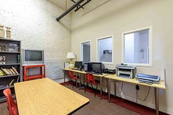 A room with a desk, chairs, and computers.